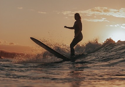 Frau surft Wellen bei Sonnenuntergang